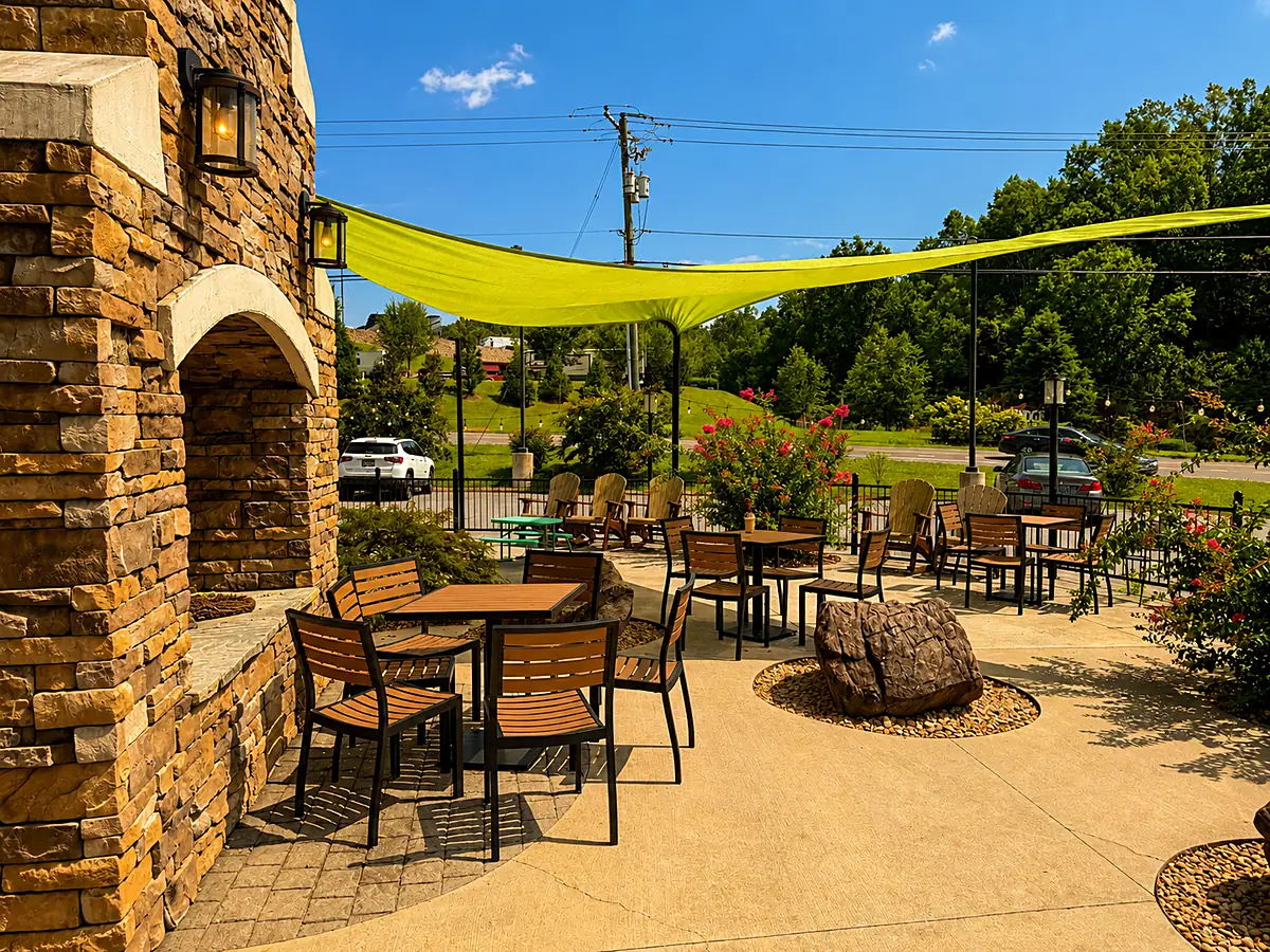 Patio tables under the shade sail beside the stone fireplace at Smoky Mountain Espresso